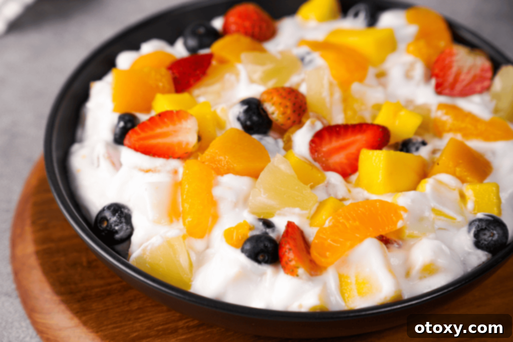 Fresh fruit salad with Cool Whip in a glass bowl, ready to be served at a summer gathering.