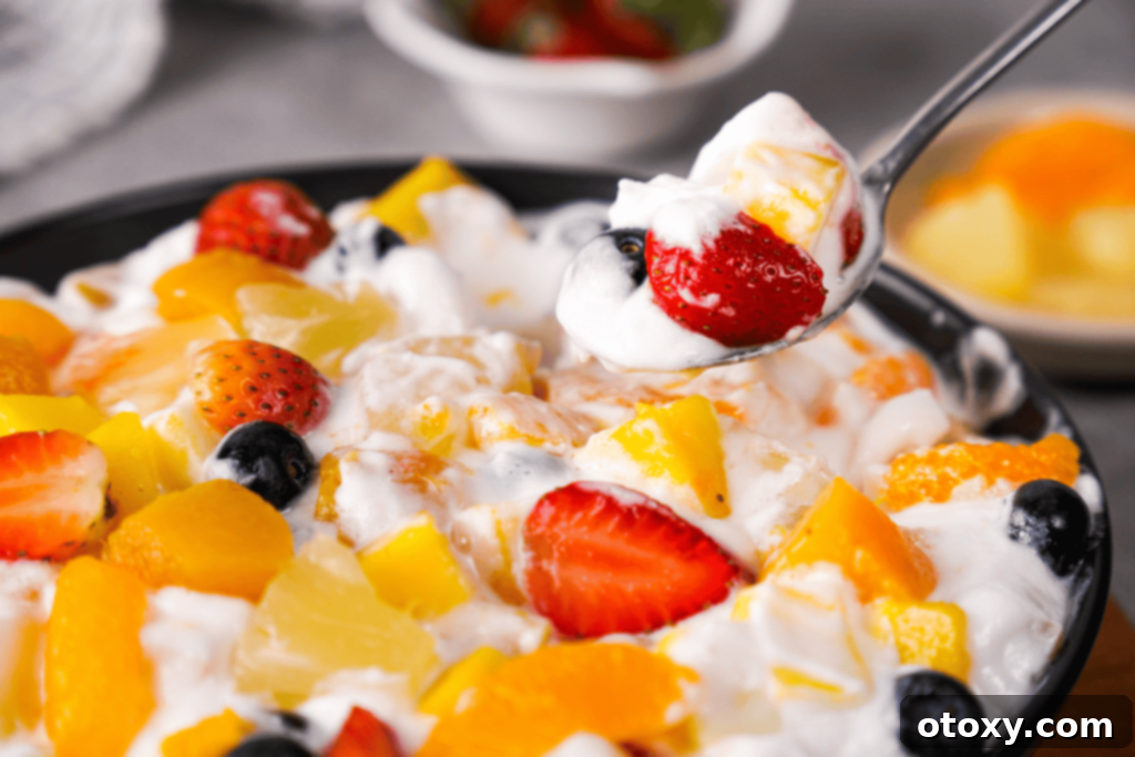 Close-up of the creamy fruit salad with Cool Whip, showing the vibrant colors of mango, strawberries, and blueberries.