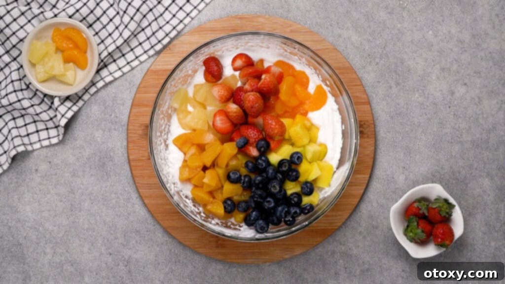 Step 3: Gently folding in the various fruits into the Cool Whip mixture.