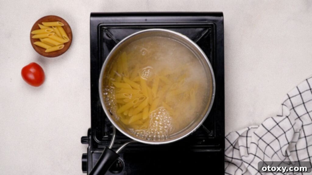 Close-up of penne pasta boiling in a large pot of salted water.