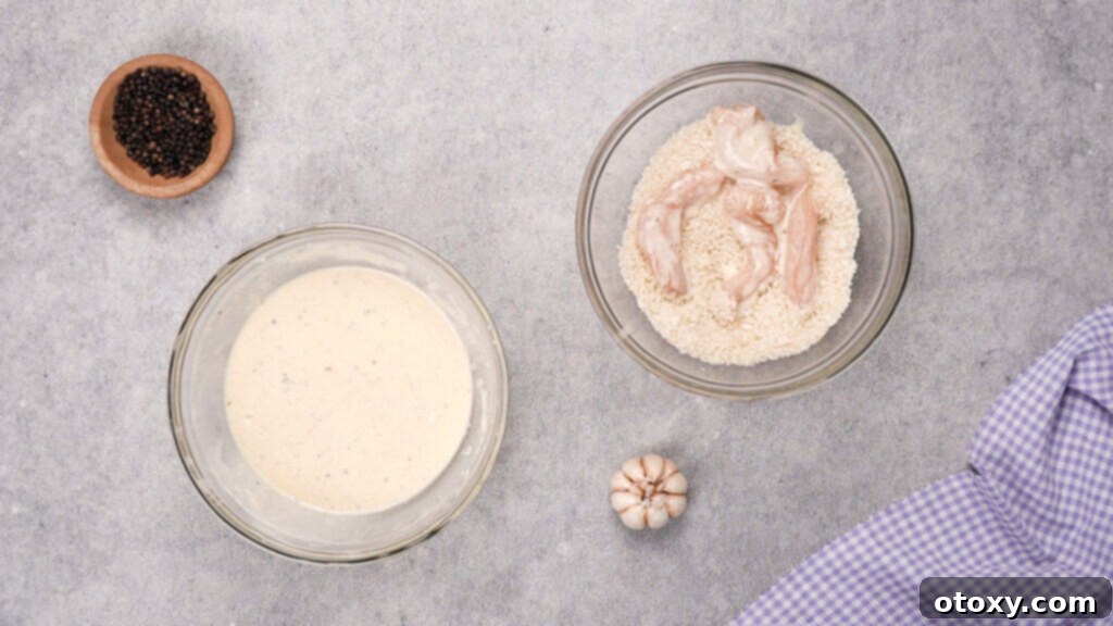 Battered chicken being coated in panko breadcrumbs