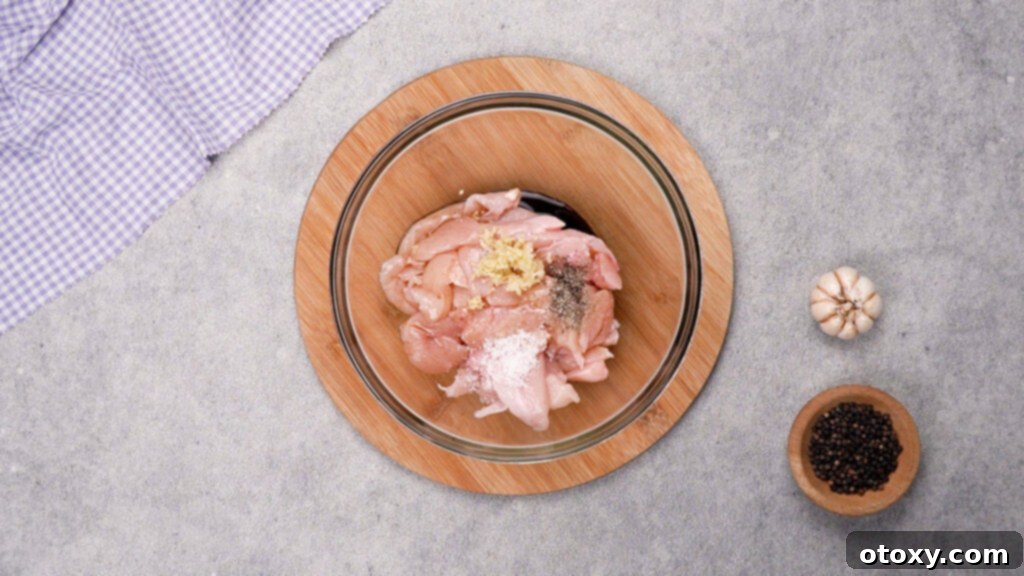 Raw chicken strips in a bowl with marinade ingredients