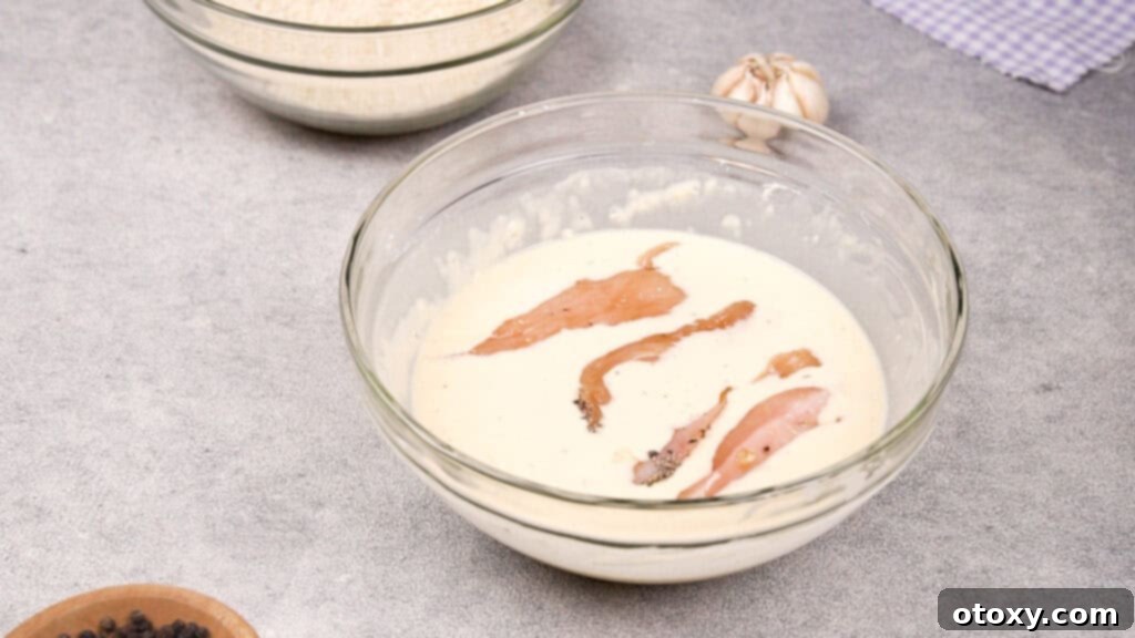 Chicken strip being dipped in batter
