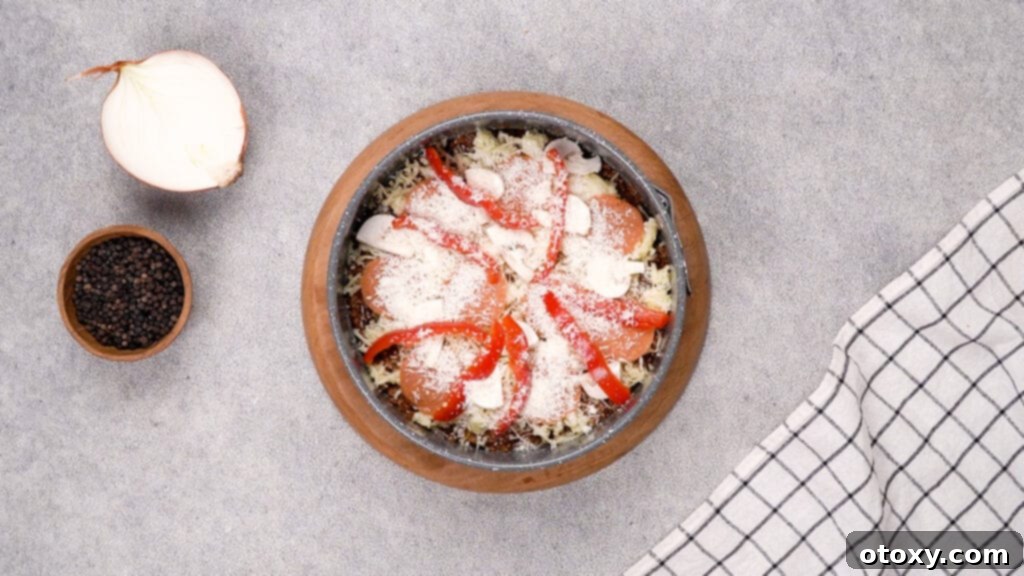 Grated Parmesan cheese sprinkled over the mozzarella and toppings of the crustless pizza.