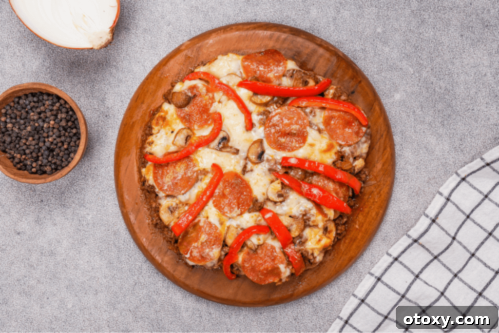 A close-up of a crustless pizza slice, showcasing the layers of meat, melted cheese, and fresh toppings.