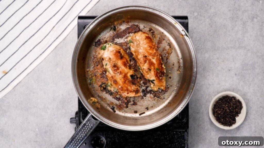 Cooking stuffed chicken breasts in a skillet, checking internal temperature with a thermometer.