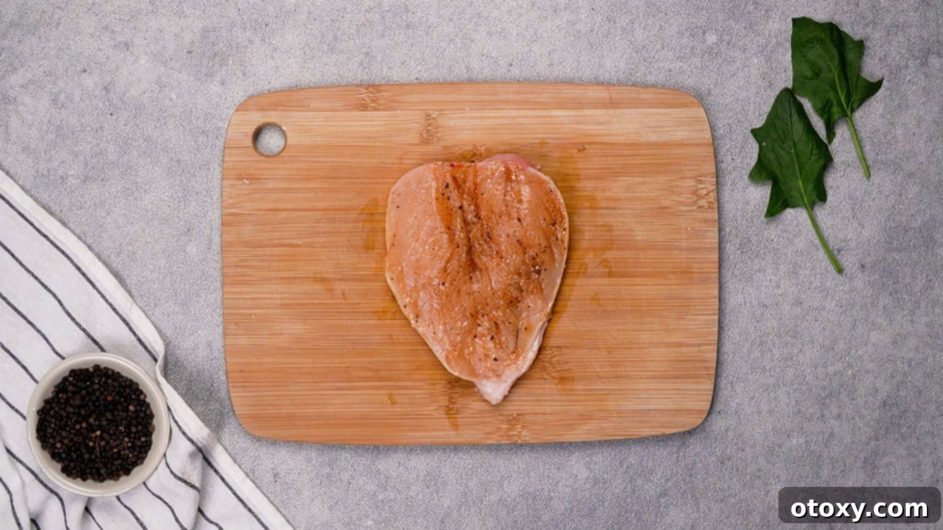 Rubbing seasoning onto butterflied chicken breast.