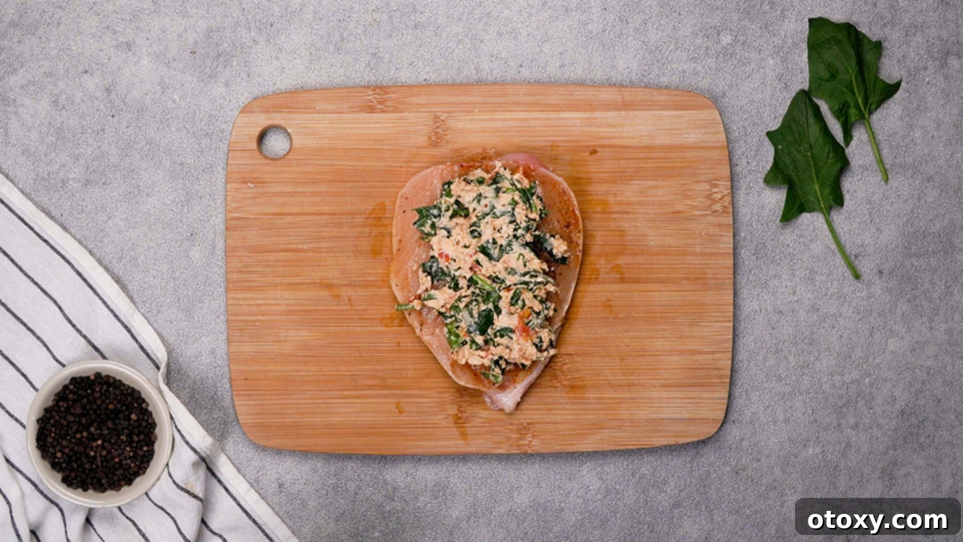 Stuffing chicken breast with creamy filling and securing with toothpicks.