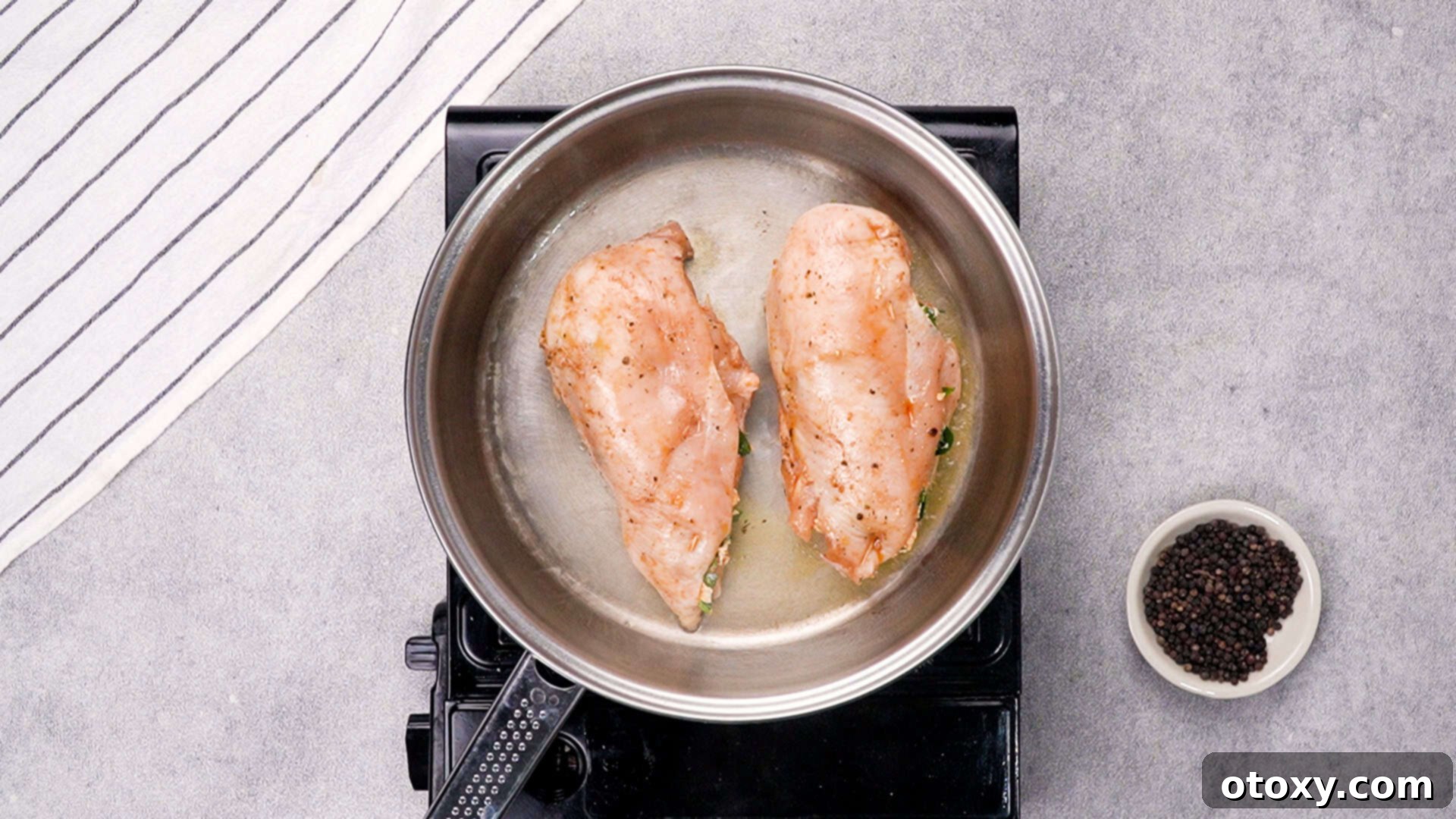 Searing stuffed chicken breasts in a hot skillet.