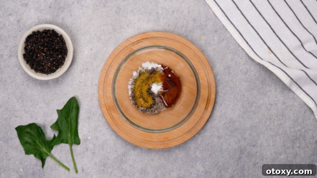 Mixing salt, pepper, paprika, and olive oil in a bowl for chicken seasoning.