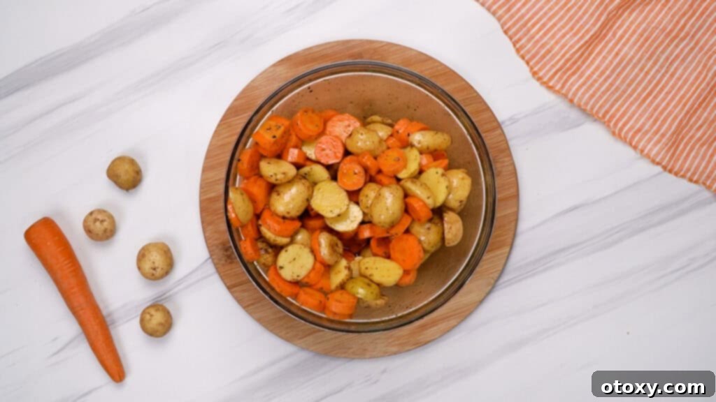 Herb Roasted Potatoes and Carrots 8 Bowl of potatoes and carrots being tossed to coat with seasonings