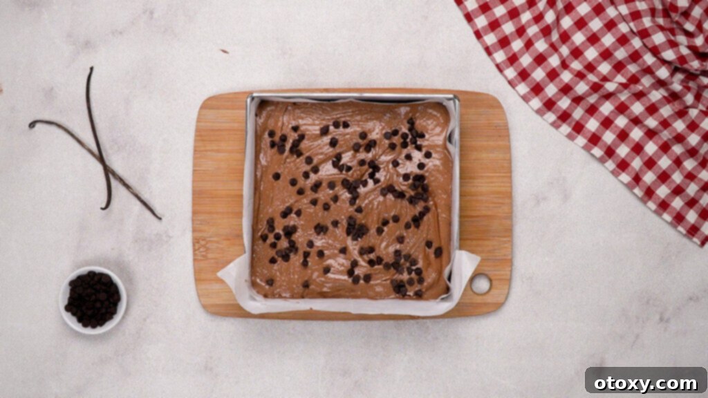 Nutella brownie batter spread in a baking pan, topped with chocolate chips