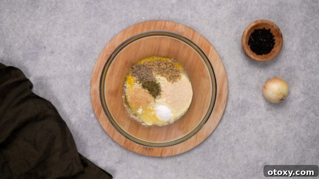 Crispy, Juicy Air Fryer Meatballs 5 Mixing bowl with dried herbs, breadcrumbs, egg, and Parmesan cheese