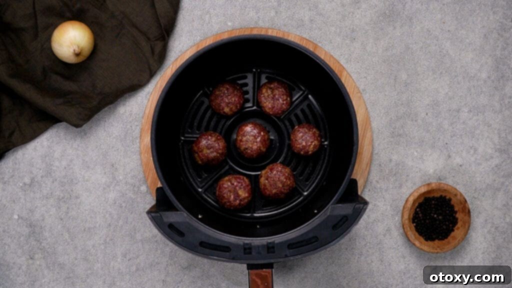 Crispy, Juicy Air Fryer Meatballs 8 Raw meatballs arranged in a single layer in the air fryer basket