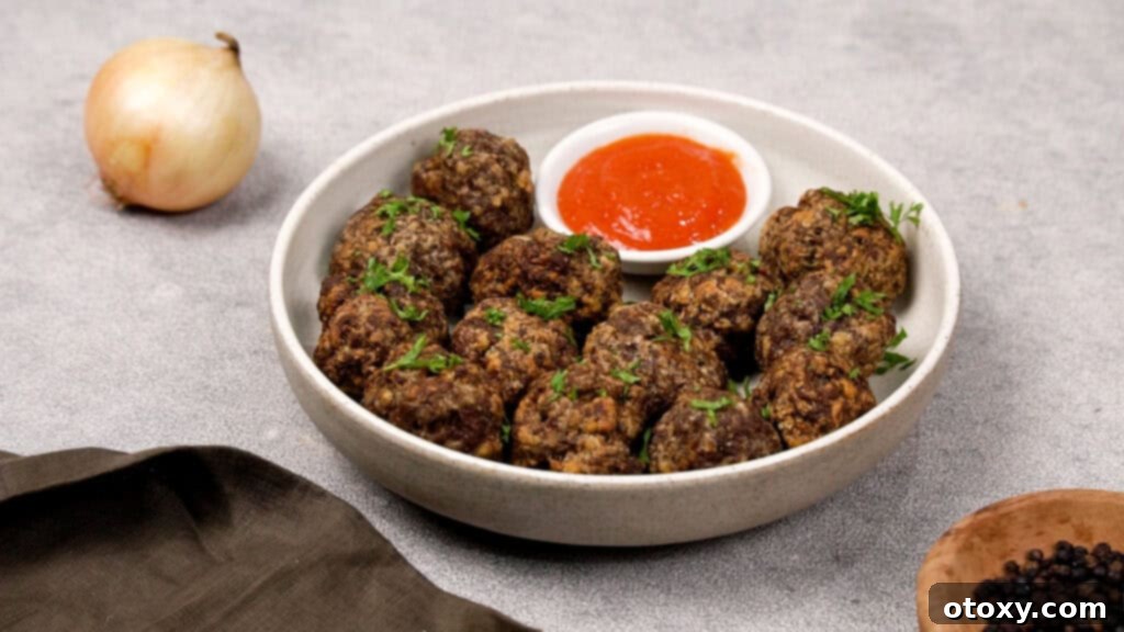 Crispy, Juicy Air Fryer Meatballs 10 Cooked air fryer meatballs resting on a plate after cooking