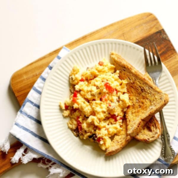 Easy scrambled eggs with a colorful medley of vegetables and a sprinkle of cheese, served on a white plate with two pieces of golden toast