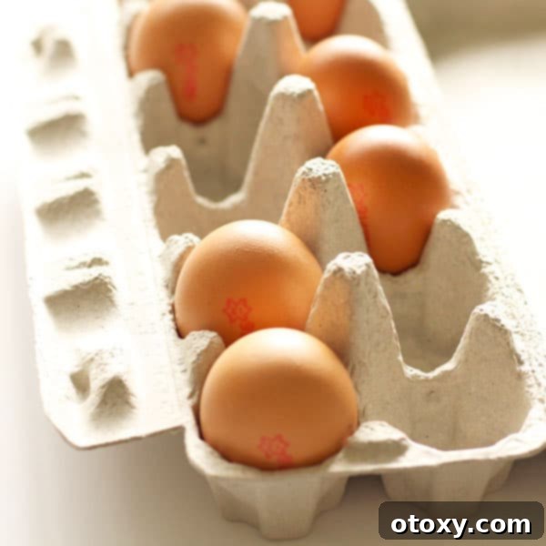An open carton of fresh brown eggs sitting on a clean white tabletop, ready for cooking.