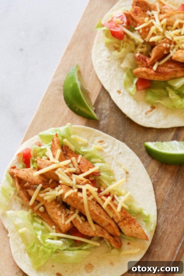 Two well-stuffed chicken tacos neatly arranged on a wooden board, ready to be enjoyed.