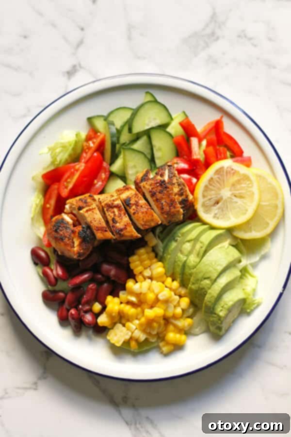 Fiesta Chicken Salad 2 Freshly prepared Mexican Chicken Salad, showcasing tender chicken, colorful vegetables, and creamy avocado on a white plate, ready to be served.