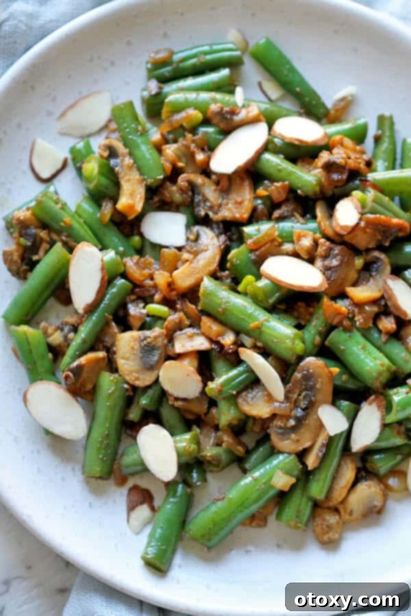 Vibrant Green Bean and Mushroom Sauté 2 sautéed green beans and mushrooms on a white plate