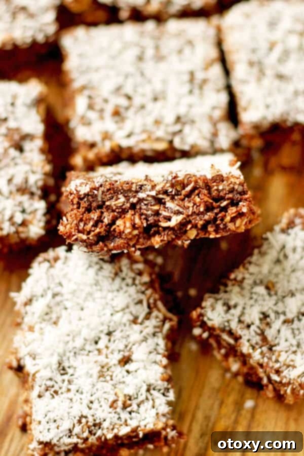Multiple slices of no-bake chocolate coconut slice on a wooden board