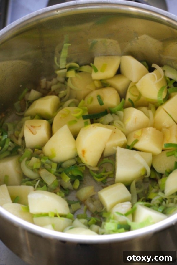 Cubed potatoes and softened leeks joining the sautéed aromatics in a large saucepan, ready for the next step.
