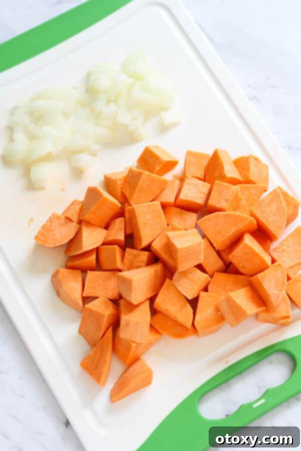 Wholesome Sweet Potato, Chickpea, and Spinach Curry 3 diced sweet potato and onion on a white cutting board