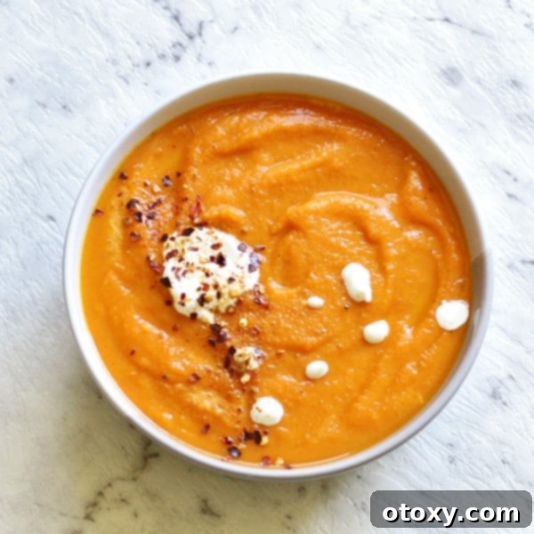 Sweet Potato and Carrot Soup, creamy and vibrant, served in a white bowl with fresh herbs.