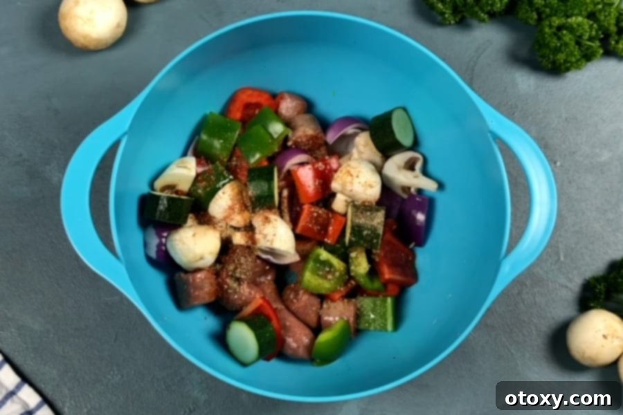 A vibrant mix of sliced sausages, zucchini, bell peppers, mushrooms, and red onion coated in olive oil and spices, ready for threading onto skewers.