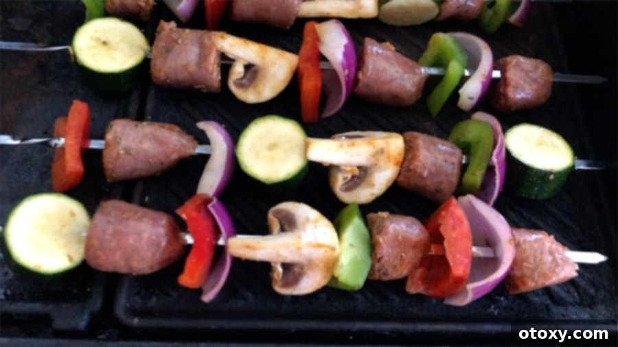 Sausage and vegetable skewers sizzling on a hot grill, showing beautiful char marks and even cooking.