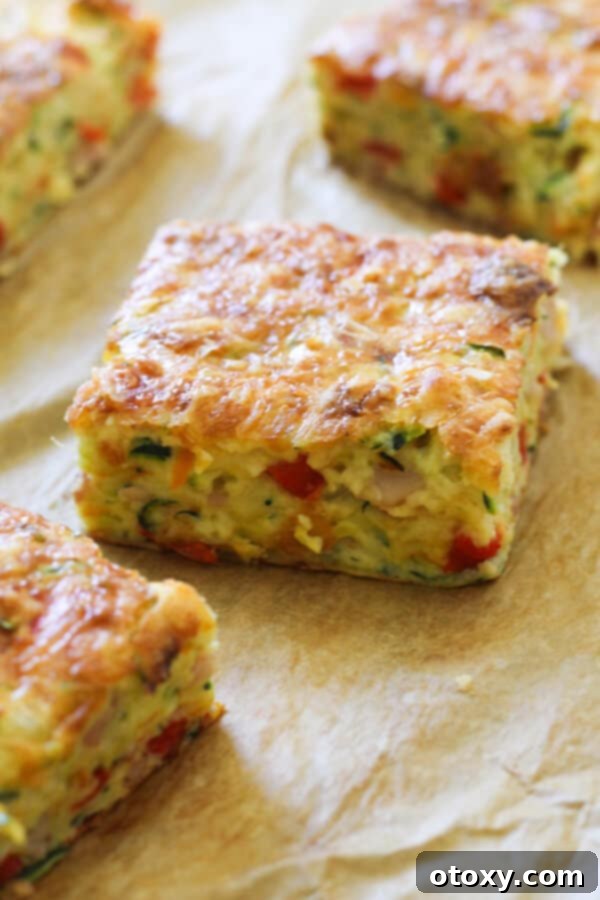 A single piece of Zucchini and Bacon Slice resting on baking paper, showcasing its perfect golden-brown crust and inviting texture.