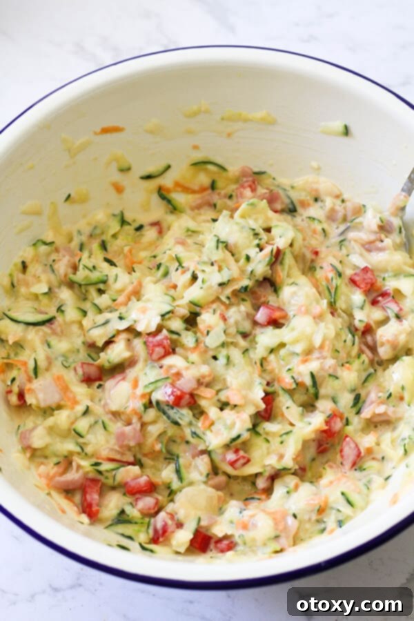 A large white mixing bowl filled with all the delicious ingredients for Zucchini and Bacon Slice, perfectly combined and ready for baking.