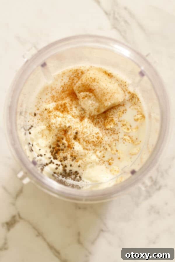 Essential ingredients for a delicious banana oat smoothie are neatly arranged within a blender cup, showcasing the simplicity and freshness before blending.