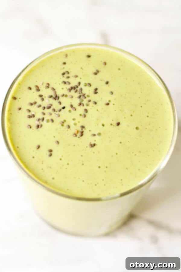 spinach mango smoothie in a glass with chia seeds sprinkled on top