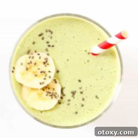 green smoothie in a glass topped with chia seeds and banana slices