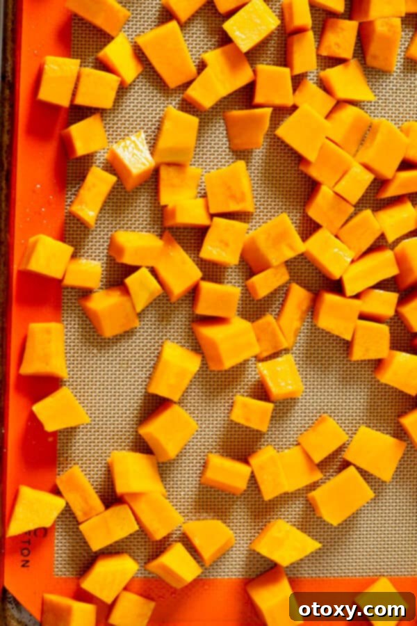 Perfectly cubed pumpkin pieces arranged on a roasting tray, drizzled with olive oil
