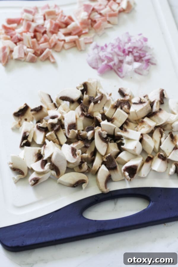 Finely diced bacon, sliced white onions, and fresh mushrooms arranged on a rustic wooden cutting board, ready for cooking.