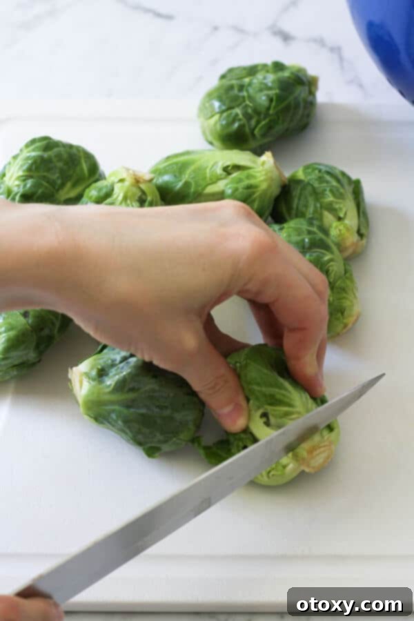 a hand demonstrating how to trim the ends of brussels sprouts