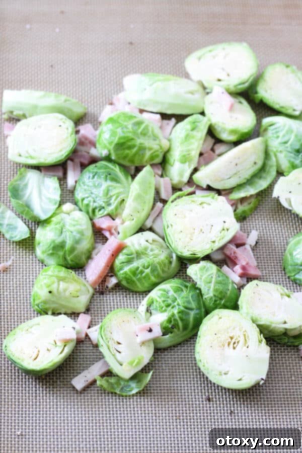 raw trimmed brussels sprouts and diced bacon on a baking tray ready for the oven