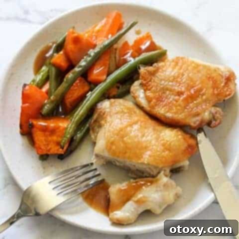 Sheet Pan Golden Chicken Thighs with Roasted Vegetables 11 Crispy chicken thighs and vegetables on a white plate ready to be served