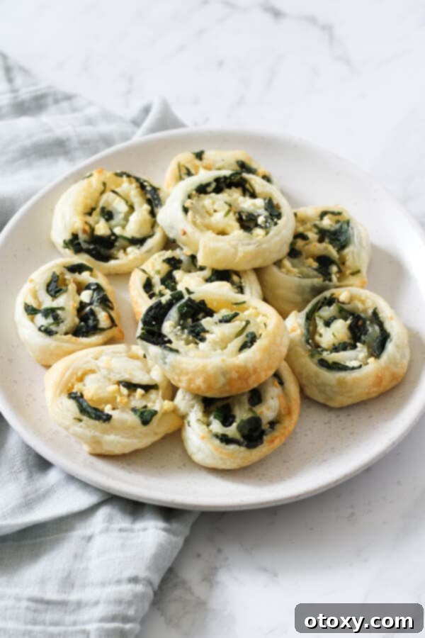 Spinach Feta Pinwheels Ready for Oven or Air Fryer 2 spinach & feta pinwheels on a white plate