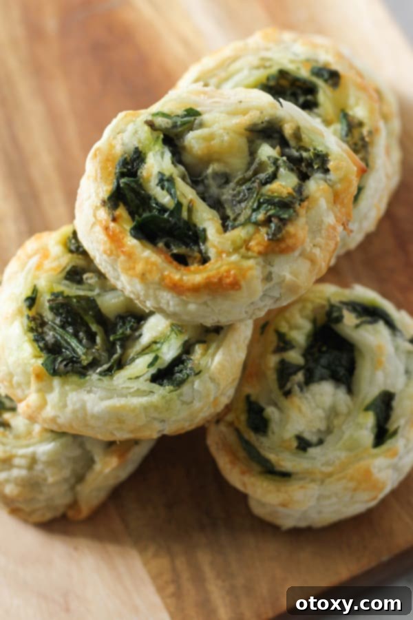 Spinach Feta Pinwheels Ready for Oven or Air Fryer 3 spinach and feta pinwheels on a wooden serving board.