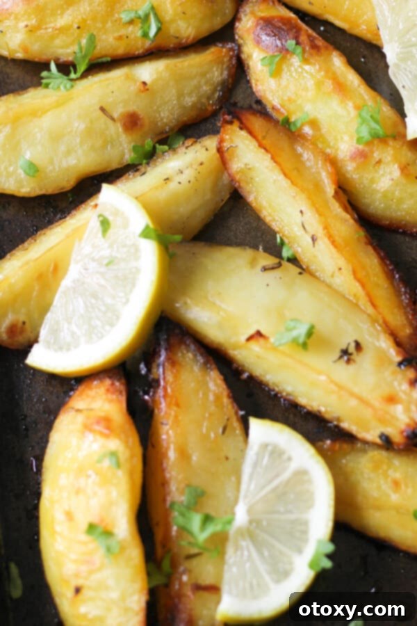 Hellenic Lemon Herb Roasted Potatoes 6 Freshly roasted Greek lemon potatoes on a baking tray, garnished with lemon slices and parsley.