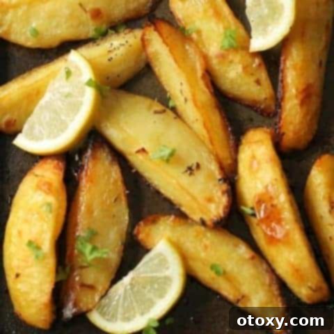 Hellenic Lemon Herb Roasted Potatoes 7 Greek lemon potatoes on a baking tray with lemon slices and parsley on top.