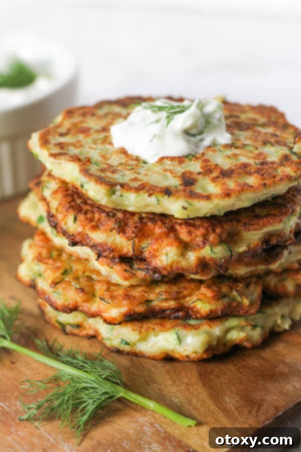a stack of zucchini fritters Kolokithokeftedes with tzatziki pooled on top