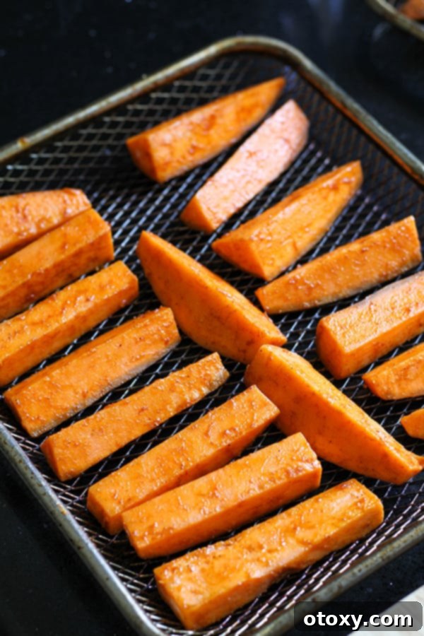 Sweet potato wedges arranged in a single layer on an air fryer wire rack, ready for cooking.