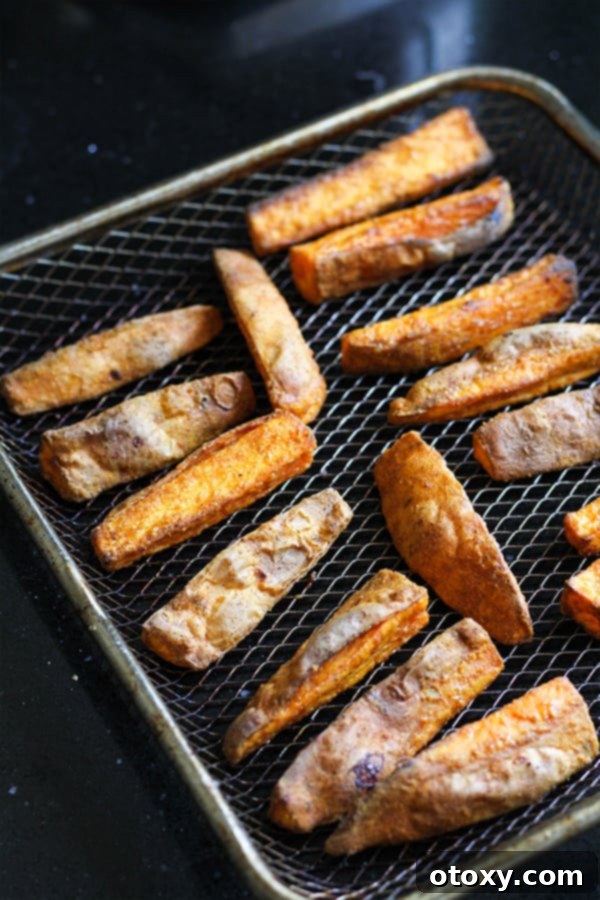 Perfectly cooked, golden-brown sweet potato wedges cooling on a wire rack.
