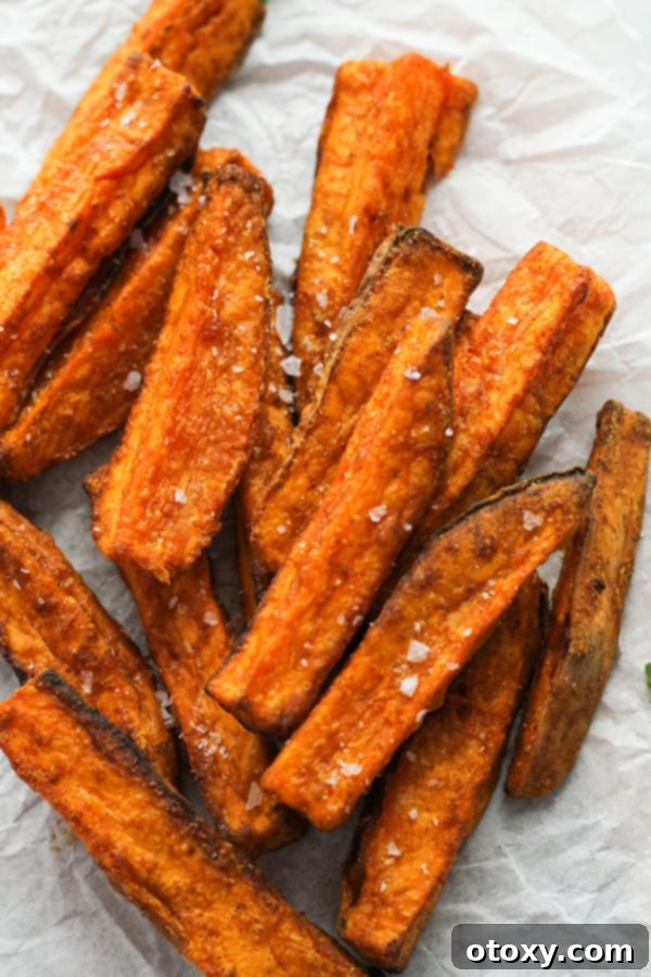 Salted sweet potato wedges resting on white baking paper, fresh out of the air fryer.
