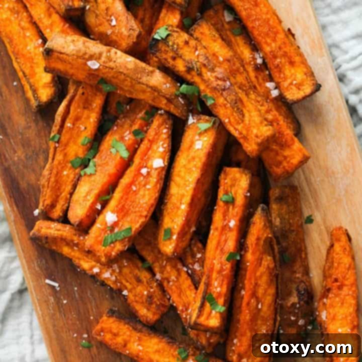 Crispy sweet potato wedges seasoned with salt, served in a rustic wooden bowl.