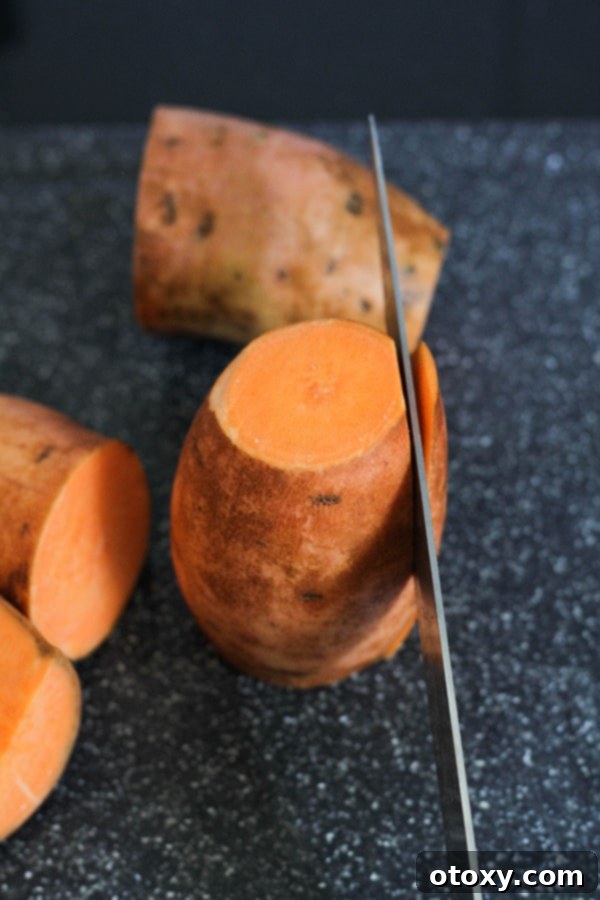 A chef's knife carefully slicing a thin edge off a sweet potato to create a flat base for stability.